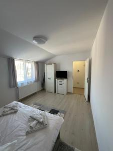 a white bedroom with a bed and a kitchen at Jokai Apartments Nr7, code entry in Sfântu-Gheorghe