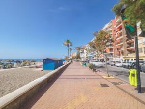 フエンヒロラにあるCubo's Apartamento Espana Fuengirola 2Bのヤシの木や建物が立ち並ぶビーチの横の歩道