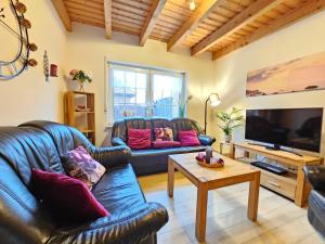 a living room with two leather couches and a tv at Ferienhaus Nordseekrabbe in Norden
