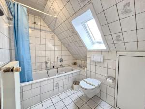 a bathroom with a toilet and a tub and a window at Ferienhaus Nordseekrabbe in Norden +36 photos