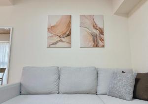 広島市にあるNeighbor's Hotel 十日市の壁に3枚の絵が描かれたリビングルームのソファ