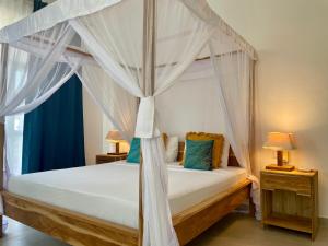 a bedroom with a canopy bed with two lamps at Ocean Boutique Hotel in Pingwe