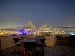 a view of the pyramids at night with tables and chairs at Tuya Pyramids View in Cairo