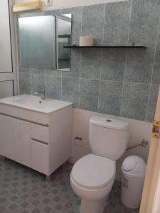 een badkamer met een toilet, een wastafel en een spiegel bij Chez Leonilde in São Filipe