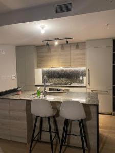 a kitchen with two bar stools at a kitchen counter at Stylist Apartment Heart of Brossard Dix30 in Brossard