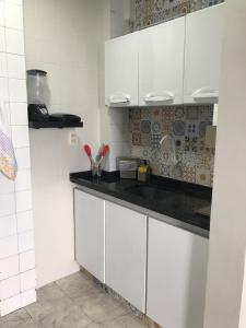 eine Küche mit weißen Schränken und einer schwarzen Arbeitsplatte in der Unterkunft Kitnet 1102 - Apartamento para temporada in Recife
