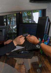 una persona que tenga un mando a distancia frente a un ordenador portátil en Hotel Boutique Tremo Bustamante, en Santiago