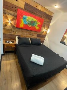 un dormitorio con una cama negra y una pintura en la pared en Hotel Boutique Tremo Bustamante, en Santiago