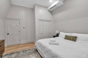 a white bedroom with a large white bed and a dresser at Carriage House Loft - King Bed and Garage Parking in Buffalo
