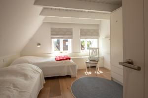 1 Schlafzimmer mit 2 Betten, einem Stuhl und einem Fenster in der Unterkunft Funkelstern in Oldsum