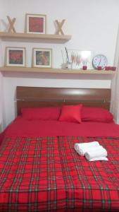 1 cama roja con 2 almohadas rojas y reloj en Romeo house en Nápoles