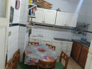 a kitchen with a table and chairs and white cabinets at The sea apartment in ‘Izbat al Qaşr