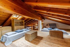 2 letti in una camera con soffitti in legno di Casa Beatrice a Courmayeur