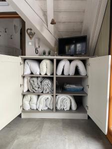 Habitación con estantes blancos, toallas y TV. en MONOLOCALE STELLALPINA - PONTE DI LEGNO-, en Ponte di Legno