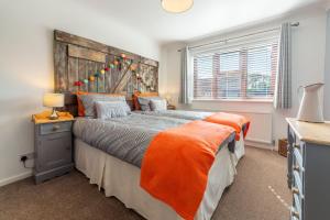 a bedroom with a large bed with an orange blanket at One Lazy Duck in Heacham