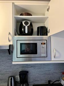 a man taking a picture of a microwave in a kitchen at Ferienwohnung 258 Haus Schleswig in Kalifornien