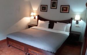 a bedroom with a bed with two lamps on the wall at Rainbow holiday home in Kalpetta