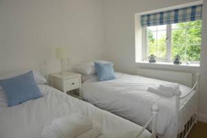 two beds in a white room with a window at Gorgeous Cottage by the sea sleeps 10 5 bed 4 bath in Heacham