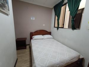 ein kleines Schlafzimmer mit einem Bett und einem Fenster in der Unterkunft alborada cuenca hospedaje in Cuenca