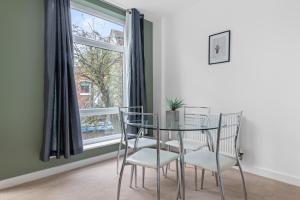 uma sala de jantar com uma mesa de vidro e cadeiras em frente a uma janela em Spacious 2 bedroom apartment opposite QMC Hospital em Nottingham