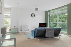a living room with a couch and a clock on the wall at Spacious 2 bedroom apartment opposite QMC Hospital in Nottingham