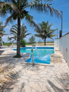 una piscina con una fuente frente a una palmera en Pousada Ykapê en Ilha Comprida