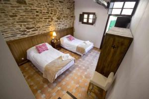 een kamer met 2 bedden en een bakstenen muur bij Casa Taboada in Sarria