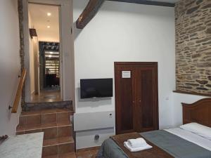 een slaapkamer met een bed en een tv aan de muur bij Casa Taboada in Sarria
