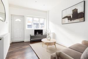 a white living room with a couch and a table at The Peckham Apartments in London