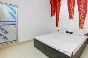1 cama en una habitación con cortinas rojas y un cartel en OYO Hotel Surya Palace, en Kushinagar