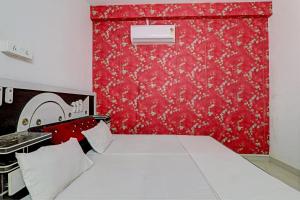 a bedroom with a bed and a red wall at OYO Hotel Surya Palace in Kushinagar