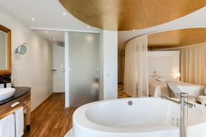 a bathroom with a white tub and a bedroom at Hotel des Balances in Lucerne