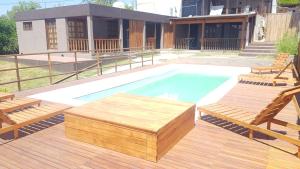 una piscina con 2 sillas y una terraza de madera en Alojamiento Tanti en Villa Santa Cruz del Lago