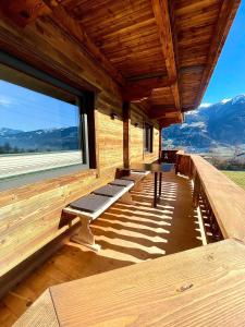 a porch of a log cabin with benches and a large window at Appartement Hirner in Fügenberg