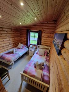 a bedroom with two beds in a log cabin at Laura's Lodge Hot Tub Log Cabin, Felmoor Park, Morpeth, Northumberland in Felton +33 photos