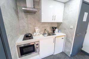 a small kitchen with a sink and a microwave at Captivating 1-Bed studio in Birmingham in Birmingham