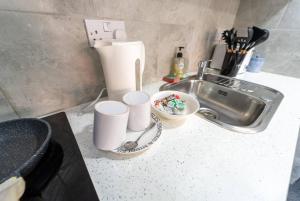 a kitchen counter with cups and a sink at Captivating 1-Bed studio in Birmingham in Birmingham