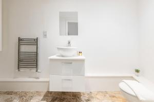 La salle de bains blanche est pourvue d'un lavabo et de toilettes. dans l'établissement The Peckham Apartments, à Londres