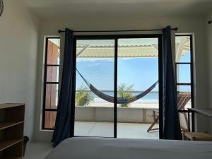 a bedroom with a bed and a window with a hammock at Stella Mar Oceanfront Hotel in Popoyo