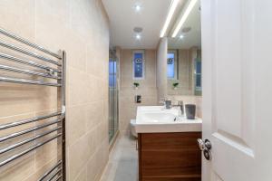 a bathroom with a white sink and a shower at The St John's Wood Apartment in London