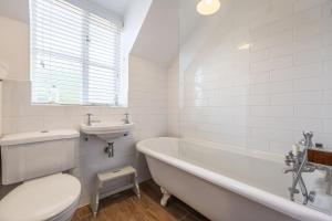 a bathroom with a tub and a sink and a toilet at Owl Cottage W in Warham +32 photos