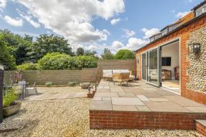 a garden with a patio and a brick building at Owl Cottage W in Warham