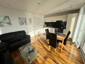 a living room with a black couch and a table at Spacious 2 Bedroom Flat Stunning Waterside View in Manchester