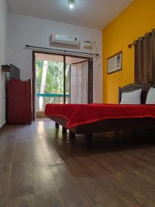 een slaapkamer met een bed met een rode deken erop bij Casa De Rocks in Calangute