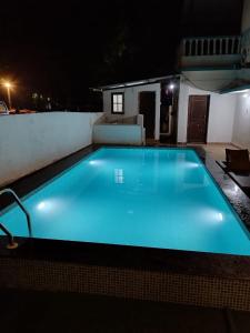 a large blue swimming pool at night at Casa De Rocks in Calangute
