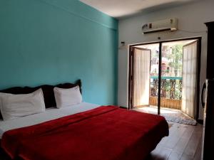 a bedroom with a bed with a red blanket and a window at Casa De Rocks in Calangute