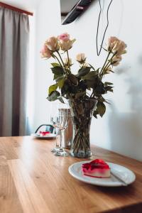 un vase de roses et une assiette de nourriture sur une table dans l'établissement Kalwados, à Radzymin
