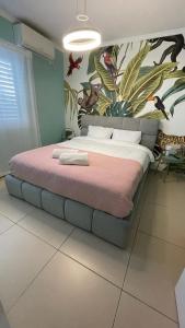 Carmel Beach Luxury Apartment في حيفا: غرفة نوم بسرير كبير عليها لوحة جدارية