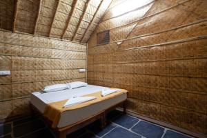 Hampi Social Resort في هامبي: غرفة صغيرة مع سرير في جدار من الطوب