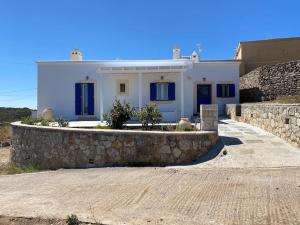 Casa blanca con ventanas azules y pared de piedra. en Tsipouras House en Kýthira